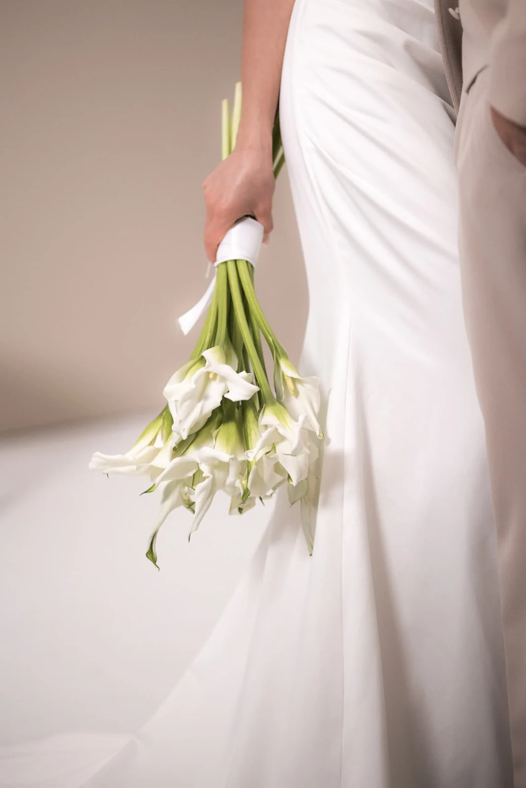 Inspirierendes Brautmotiv: fließendes weißes Kleid mit weißem Blumenstrauß