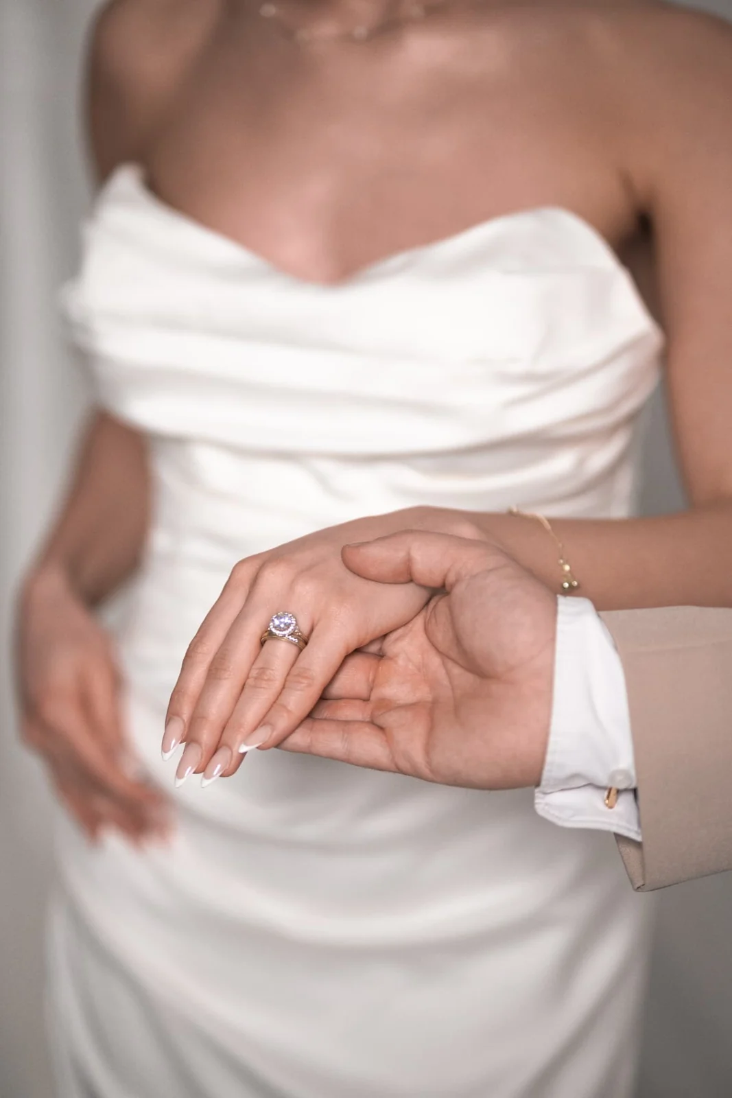 Nahaufnahme einer Braut im weißen Kleid, deren Hand mit Ring gehalten wird
